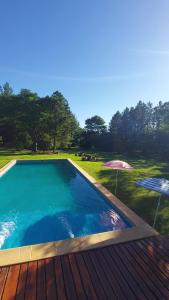 a swimming pool with a wooden deck and an umbrella at Quinta Cáceres in Santa Ana