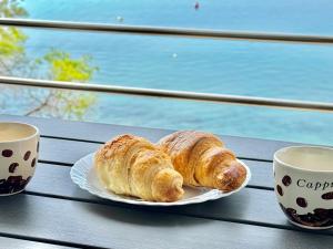 two croissants on a plate on a table with two cups at Apartman Nina Selce in Selce