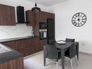 a kitchen with a table and chairs and a clock on the wall at Zenia Court in Marsaskala