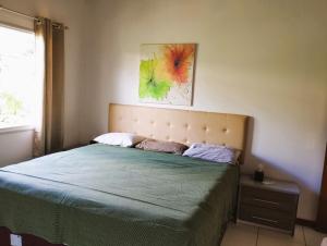1 dormitorio con 1 cama y una pintura en la pared en Residence Cotê d' Azur, en Imbassai
