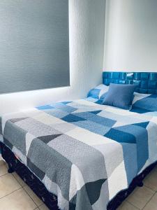Una cama azul y blanca en una habitación en Tiny house Santa Ana en Santa Ana