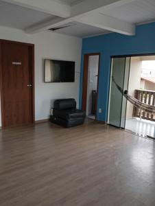 sala de estar con silla negra y TV de pantalla plana en Pousada Hawaii, en Barra Velha