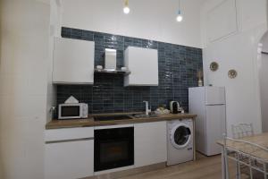 a kitchen with white cabinets and a washer and dryer at Maison Sara in Bari