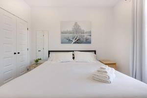 a white bedroom with a white bed with towels on it at M11 Neat & Spacious 1BR in Heart of Plateau MTL in Montréal