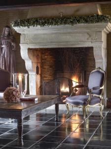 a living room with a fireplace and a table and chairs at B&B Hof te Spieringen in Vollezele