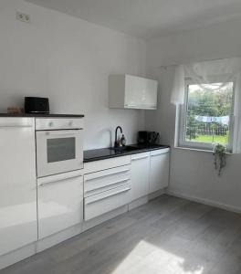 eine weiße Küche mit weißen Schränken und einem Fenster in der Unterkunft HOME OF VACATION - Landhausstil zum Wohlfühlen - FREE WIFI & NETFLIX in Adelheidsdorf