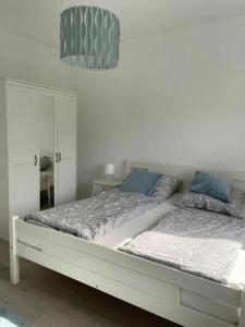 ein weißes Bett mit blauen Kissen im Schlafzimmer in der Unterkunft HOME OF VACATION - Landhausstil zum Wohlfühlen - FREE WIFI & NETFLIX in Adelheidsdorf