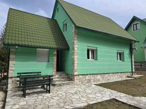 un edificio verde con un banco delante en Guest House Boka, en Žabljak