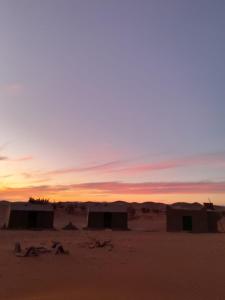 grupa chatek na pustyni o zachodzie słońca w obiekcie Wüstencamp in Erg Chegaga w mieście Mhamid