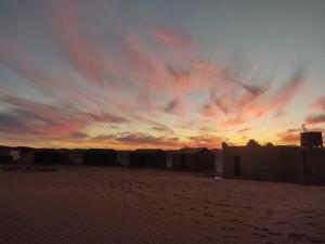 a sunset in the desert with tents in the sand at Wüstencamp in Erg Chegaga in Mhamid