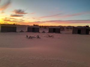 a group of huts in the desert at sunset at Wüstencamp in Erg Chegaga in Mhamid