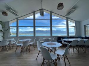 Habitación con mesas, sillas y ventanas grandes. en Kaikoura Seaside lodge, en Kaikoura