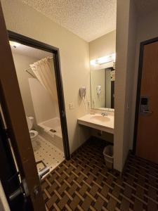 ein Badezimmer mit einem Waschbecken, einem WC und einem Spiegel in der Unterkunft Crossroads Hotel 