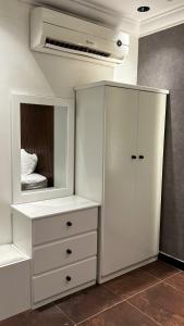 a bedroom with a white cabinet and a mirror at أبها مارينا فيلا in Abha