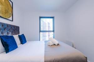 1 dormitorio con 1 cama blanca grande con almohadas azules en Windmill Suite- Modern 2 bed 2 bath with concierge perfect for leisure, business and contractor stays by Dreamluxe en Birmingham