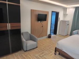 1 dormitorio con 1 cama, 1 silla y TV en Jeddah Grand Beach, en Yeda