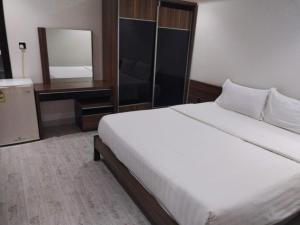 1 dormitorio con 1 cama blanca grande y espejo en Jeddah Grand Beach, en Yeda