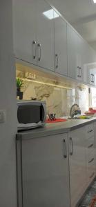 a kitchen with white cabinets and a microwave on a counter at Flat rent berat in Berat