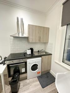 a kitchen with a sink and a washing machine at Chapel studios in Ilford