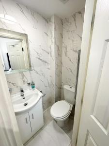 a white bathroom with a toilet and a sink at Chapel studios in Ilford