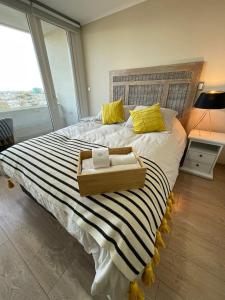 a large bed with yellow pillows and a wooden box on it at Acogedor Departamento estudio en centro de Chillán in Chillán