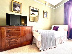 a bedroom with a bed and a dresser with a television at Colthrop Manor with Gardens in Thatcham