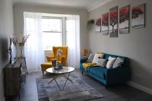 - un salon avec un canapé bleu et une table dans l'établissement Falkirk City Centre Stylish Two-Bedrooms Apartment, à Falkirk
