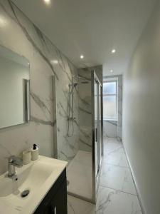 La salle de bains est pourvue d'une douche, d'un lavabo et d'un miroir. dans l'établissement Falkirk City Centre Stylish Two-Bedrooms Apartment, à Falkirk