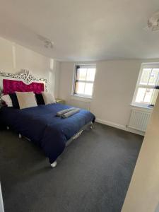 - une chambre avec un lit bleu avec une tête de lit rouge et 2 fenêtres dans l'établissement 4 Bedroom House Central Oxford, à Oxford