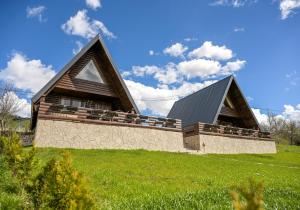 a house on top of a hill with a green field at Cottages Relax in Jajce