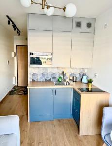 uma cozinha com armários azuis e um lavatório em L7 Warsaw Apartments Sauna&Gym em Varsóvia