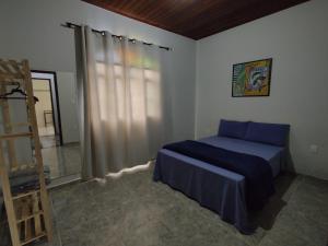 a bedroom with a blue bed and a mirror at Casa Amarela Hostel in Barão de Cocais