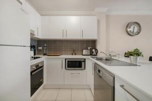 雪梨的住宿－Walk to Coogee Beach Apartment Retreat，白色的厨房配有白色橱柜和水槽