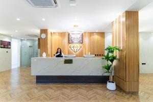 a woman sitting at a reception desk in a lobby at جوهرة مسقط للشقق الفندقية in Ma‘ābīlah