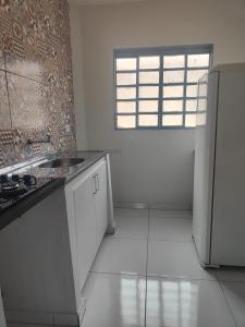 a white kitchen with a sink and a window at Aconchego in Campo Grande