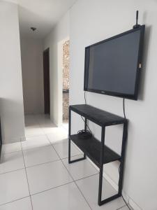 a flat screen tv on a black stand in a room at Aconchego in Campo Grande