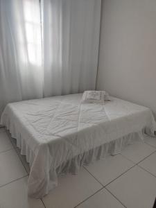 a bed with a white sheet on it in a room at Aconchego in Campo Grande