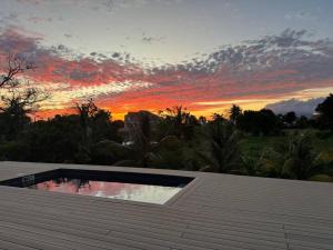 a swimming pool on top of a roof with a sunset at Villa Mahé, Majestueuse villa avec piscine, F4 à Ducos in Ducos