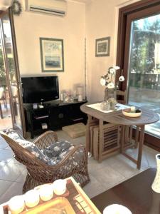 een woonkamer met een tafel en een televisie bij Casa al mare con giardino in Alghero