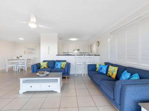 a living room with a blue couch and a kitchen at Ocean Outlook on Marine Parade in Kingscliff