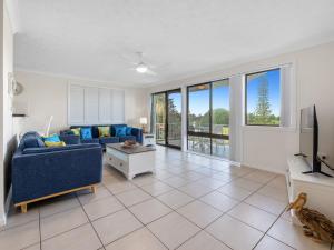 a living room with a blue couch and a tv at Ocean Outlook on Marine Parade in Kingscliff