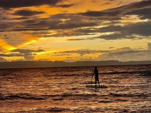a person standing on a paddle board in the ocean at Camotes Island Beachfront Vacation House in San Francisco