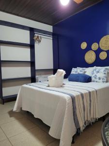a bedroom with a bed with a blue wall at Casa Meu Cantinho in Barra de São Miguel
