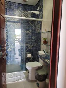 a blue tiled bathroom with a toilet and a shower at Casa Meu Cantinho in Barra de São Miguel