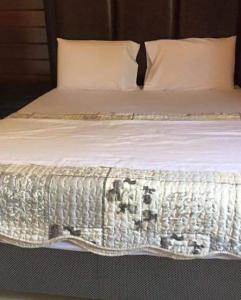a bed with a white comforter on it at Resort Nabruni in Belas