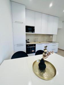 a kitchen with white cabinets and a vase on a table at Apartment Riviéra Centrum, private parking and smart check in in Banská Bystrica