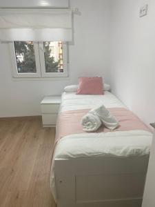 een wit bed met een roze kussen en handdoeken erop bij DH Apartamento Turistico in Cangas de Onís