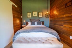 1 dormitorio con 1 cama grande y pared de madera en Cabanas da Fazenda, en Gramado