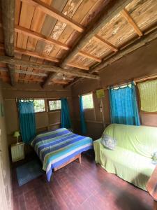 a bedroom with two beds and blue curtains at Eco Posada Tierra Fértil in Santa Ana