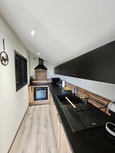 une cuisine avec un comptoir noir et des placards en bois dans l'établissement Maison d'une chambre avec sauna jardin amenage et wifi a Les Forges, à Les Forges